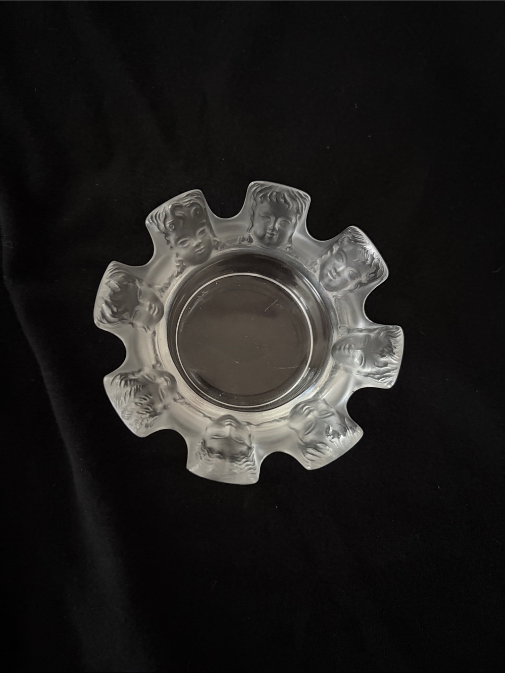 Lalique crystal glass dish with ornate faces sculpted along the ridge.